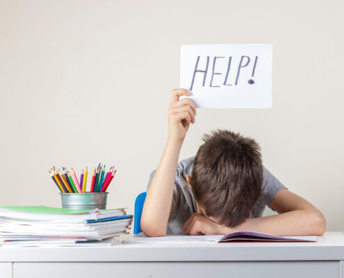 Resignierter Schüler mit Hilfe-Schild in der Hand